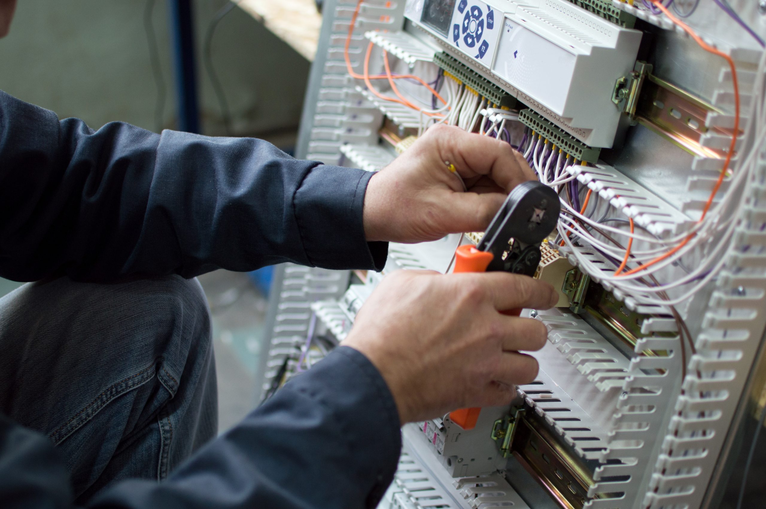 An image of an electrician's hand assembling industrial control cubicle in a workshop